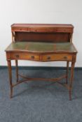 A mahogany serpentine fronted writing desk with three green leather inset panels with shelf above