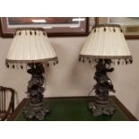 An ornate pair of spelter cherub table lamps with shades,