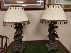 An ornate pair of spelter cherub table lamps with shades,