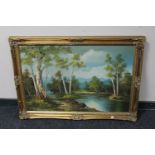 A gilt framed oil on board depicting a river through a wooded landscape
