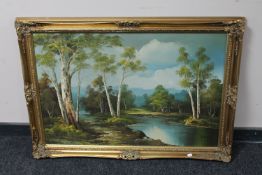 A gilt framed oil on board depicting a river through a wooded landscape