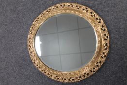 An ornate gilt oval framed mirror