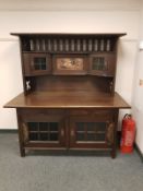 An oak Arts and Crafts sideboard with copper detail and inset panel,