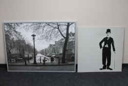 A large framed Ikea print of Amsterdam and a framed canvas of Charlie Chaplin