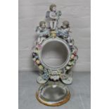 An ornate china dressing table mirror surmounted by three cherubs with flower encrusted decoration