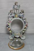 An ornate china dressing table mirror surmounted by three cherubs with flower encrusted decoration