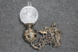 A Victorian cast patinated wall bracket with oil lamp and glass shade