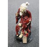 A Chinese pottery figure of an elderly man on circular wooden base