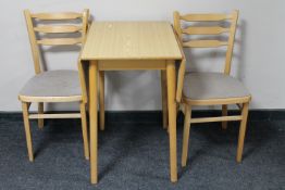 A drop leaf kitchen table together with two chairs