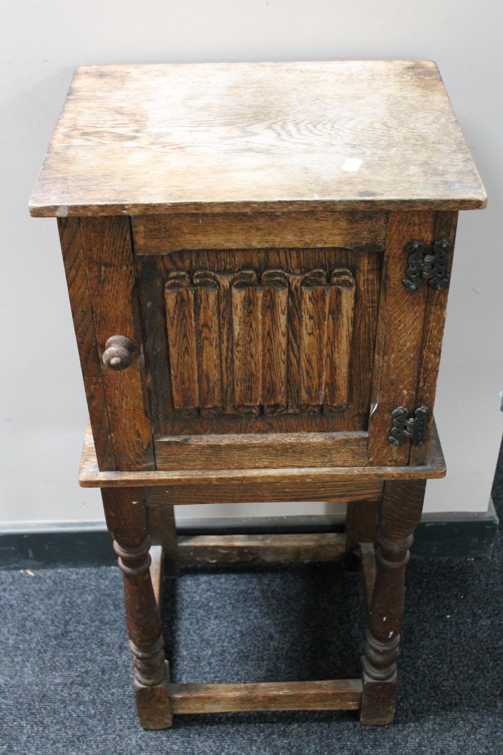 An oak linen fold pot cupboard on raised legs