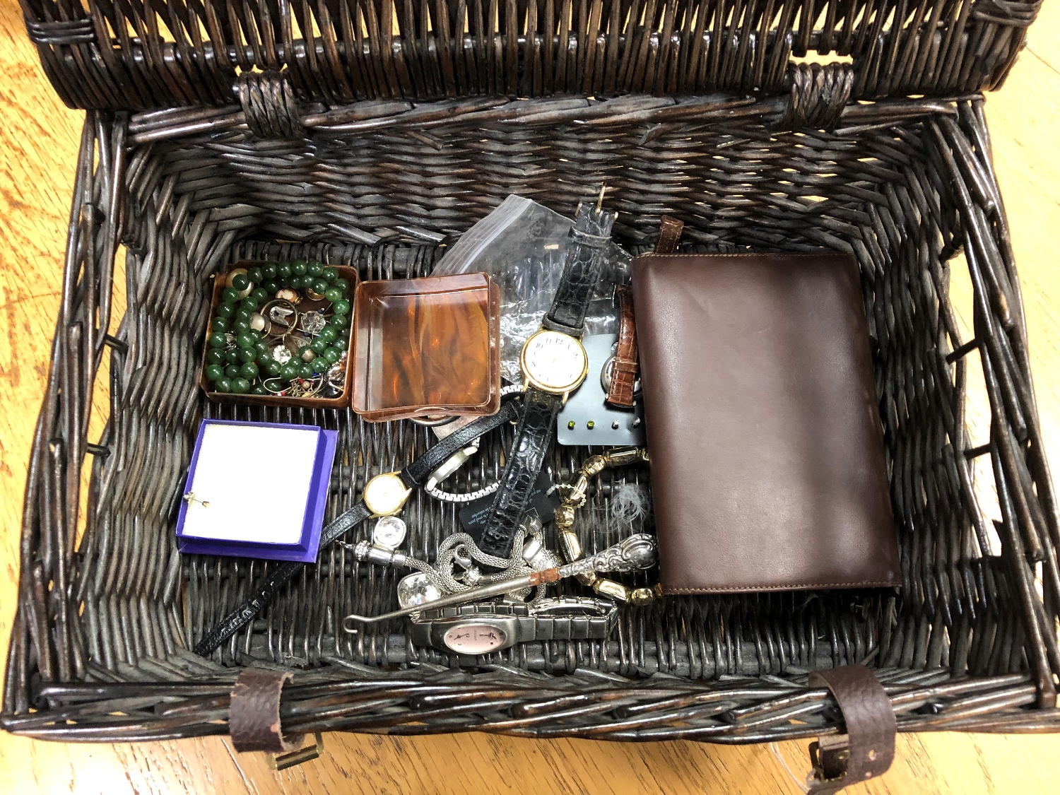 A wicker basket of costume jewellery, wristwatches, studs,