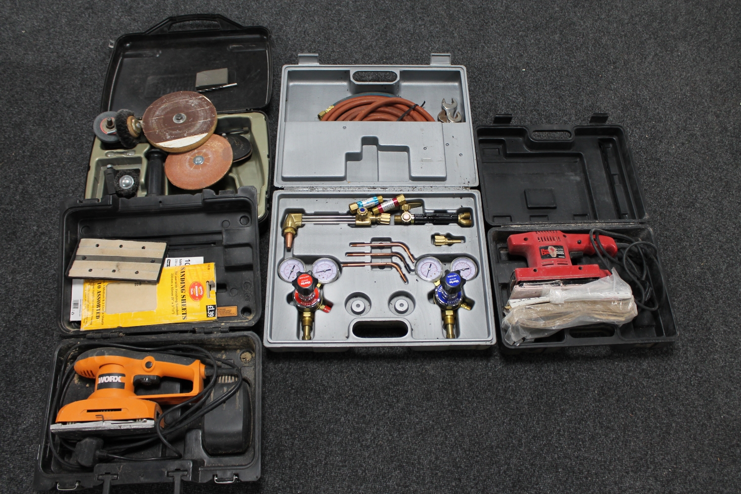 A box of two cased electrical sanders, gas welding kit,