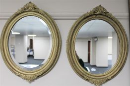 A pair of decorative gilt oval framed mirrors