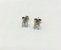 A pair of solitaire diamond earrings in platinum.