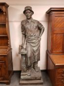 An impressive patinated bronze life size figure of a blacksmith holding a hammer, height 195 cm.