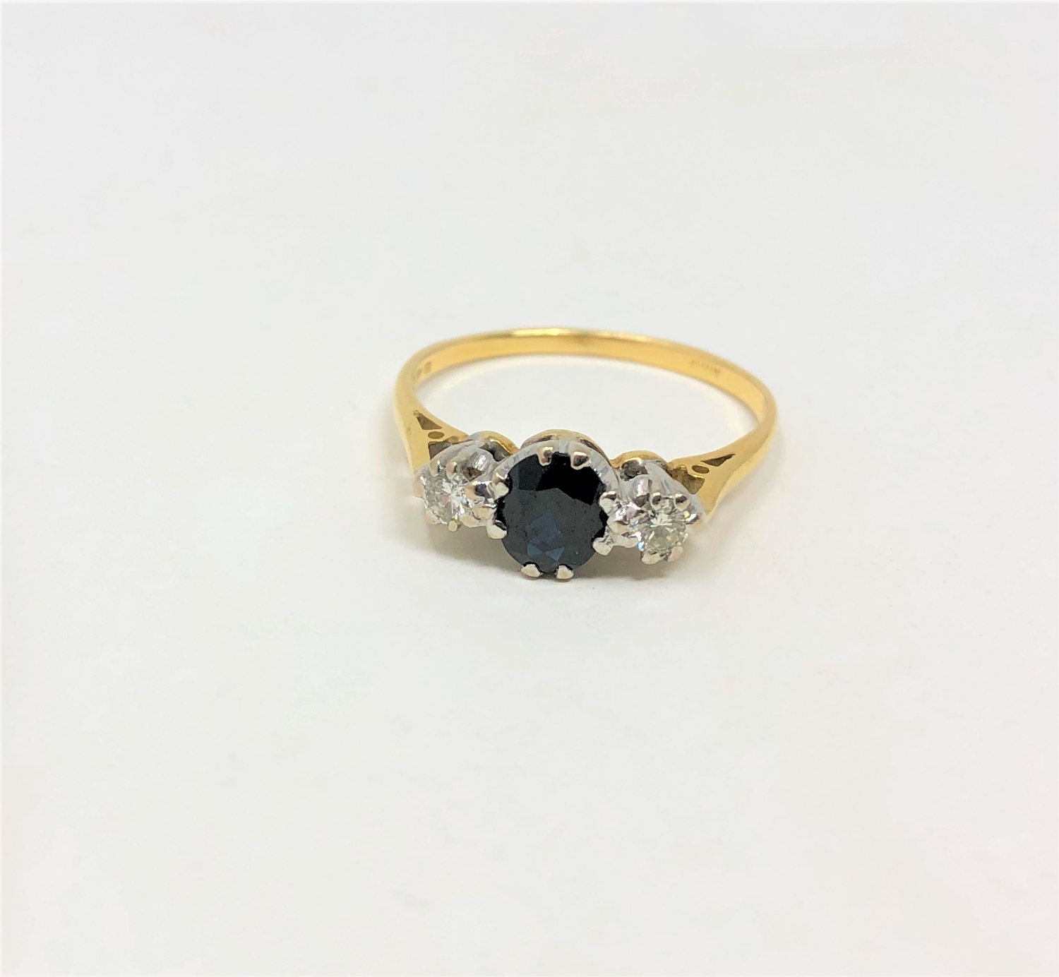 An 18ct gold sapphire and diamond three stone ring, the oval sapphire weighing an estimated 0.