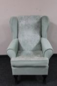 A wingback armchair upholstered in green dralon