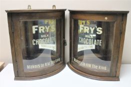 A pair of Edwardian and later oak glazed door wall cabinets with Fry's Chocolate advertising