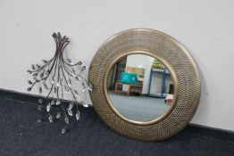 A circular metal framed mirror and piece of metal wall art