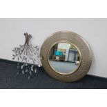 A circular metal framed mirror and piece of metal wall art