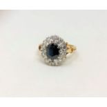 An 18ct gold diamond and sapphire cluster ring, the oval sapphire weighing approximately 1.