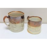 Two antique stoneware mugs depicting hunting and farming scenes.