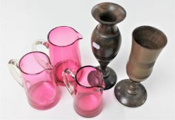 Three cranberry glass jugs,