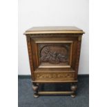 A continental carved oak panel door cabinet fitted with a drawer on raised legs