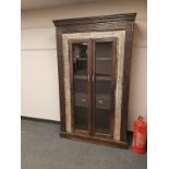 An Eastern carved hardwood glazed double door cabinet fitted with two drawers ,