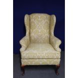 A wingback armchair in gold and cream fabric