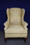 A wingback armchair in gold and cream fabric
