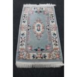 A fringed Chinese embossed rug on green ground,