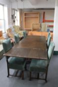 An oak table on X-frame base and six green dralon upholstered dining chairs