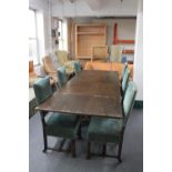 An oak table on X-frame base and six green dralon upholstered dining chairs