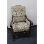 An early 20th century carved oak scroll arm armchair in tapestry fabric
