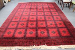 A machine made Persian style fringed carpet on red ground,