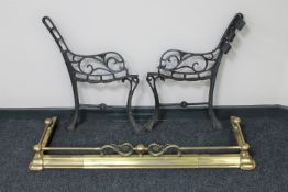 An antique brass extending fire curb and a pair of cast iron garden bench ends