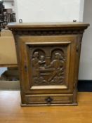 An early twentieth century carved oak wall cabinet with panel door fitted with a drawer