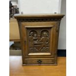 An early twentieth century carved oak wall cabinet with panel door fitted with a drawer