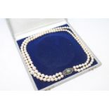 A continental two-strand cultured pearl necklace on 14ct gold diamond and green paste set clasp