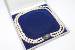 A continental two-strand cultured pearl necklace on 14ct gold diamond and green paste set clasp