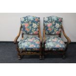 A pair of carved oak scroll arm armchairs in floral fabric