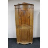 A 19th century continental pine bow fronted double corner cabinet