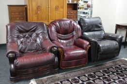A wooden framed Burgundy leather armchair together with a leather chair and brown leather Lazy-boy