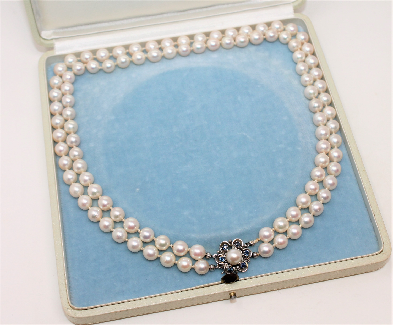 A continental two-strand cultured pearl necklace on 14ct white gold sapphire set clasp, length 44cm.