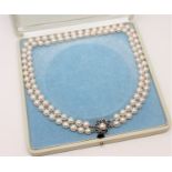 A continental two-strand cultured pearl necklace on 14ct white gold sapphire set clasp, length 44cm.