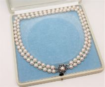 A continental two-strand cultured pearl necklace on 14ct white gold sapphire set clasp, length 44cm.