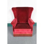 An early 20th century wing back armchair in red dralon