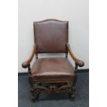 An early 20th century carved oak armchair in brown leather