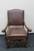 An early 20th century carved oak armchair in brown leather